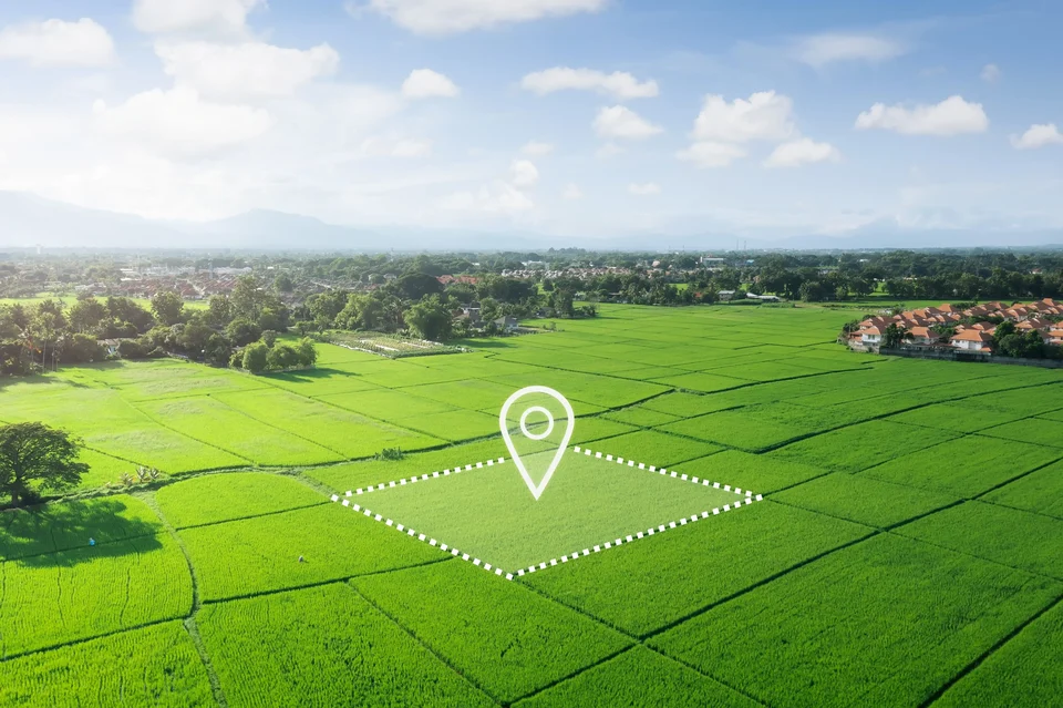 Green farmland with one plot marked out and a location pin