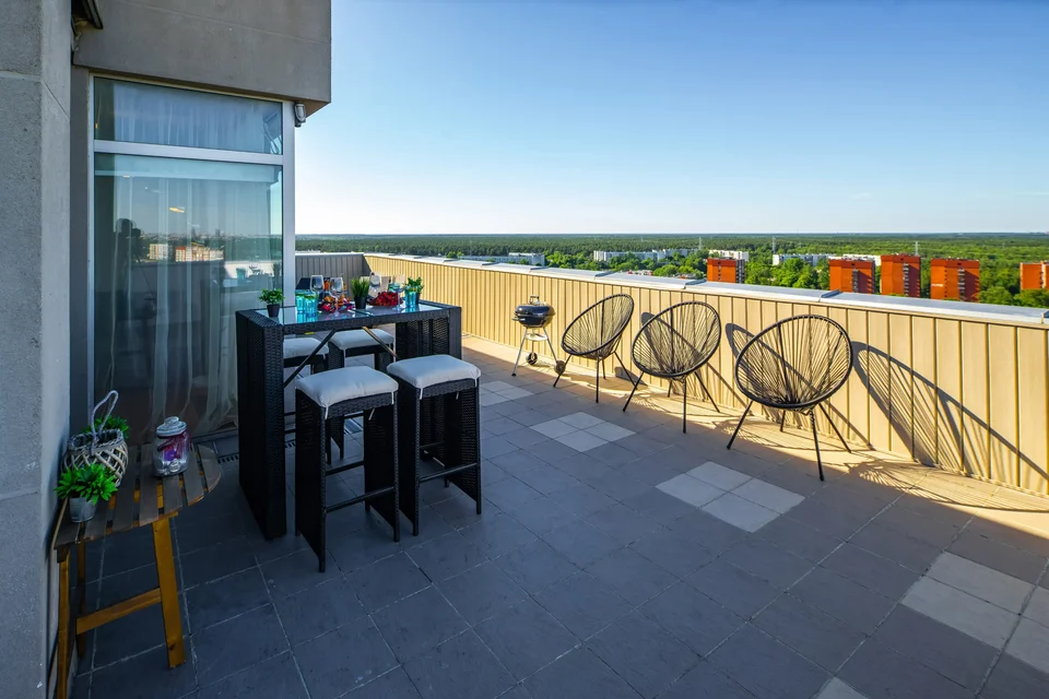 A rooftop terrace with a bar counter, stools and wicker chairs