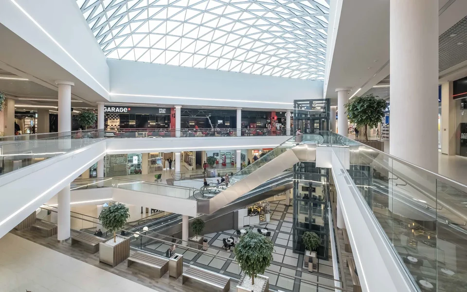 A shopping mall atrium with a glass roof and escalators