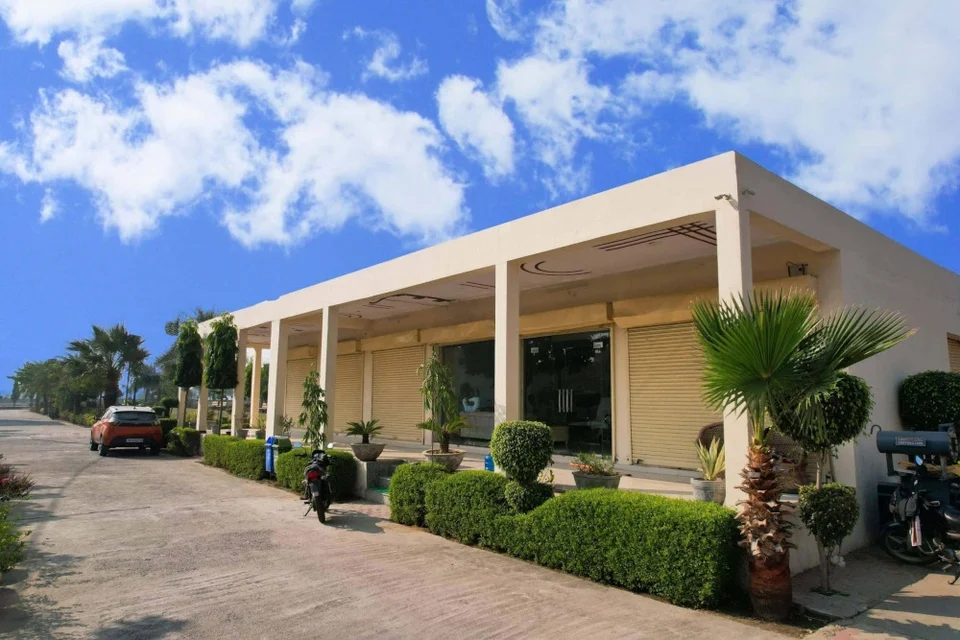 A single-storey building with a colonnade and hedges at Krishna Vihar