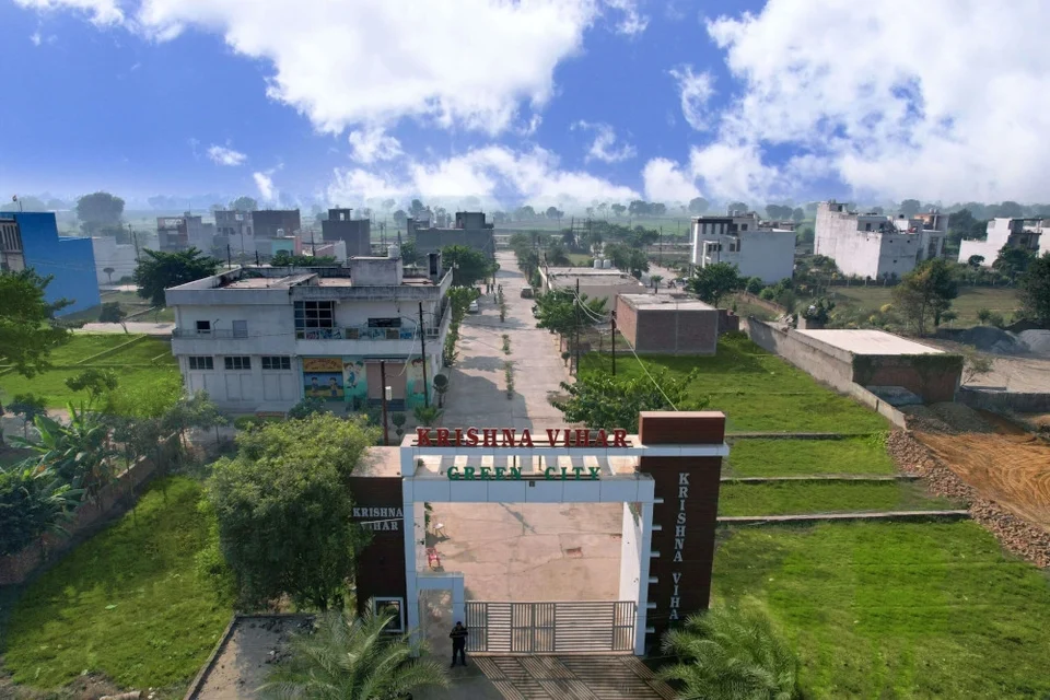 Krishna Vihar's entrance gate seen from above, with homes and plots beyond