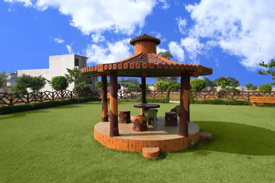 A wooden gazebo on a lawn at Mahadev Vihar