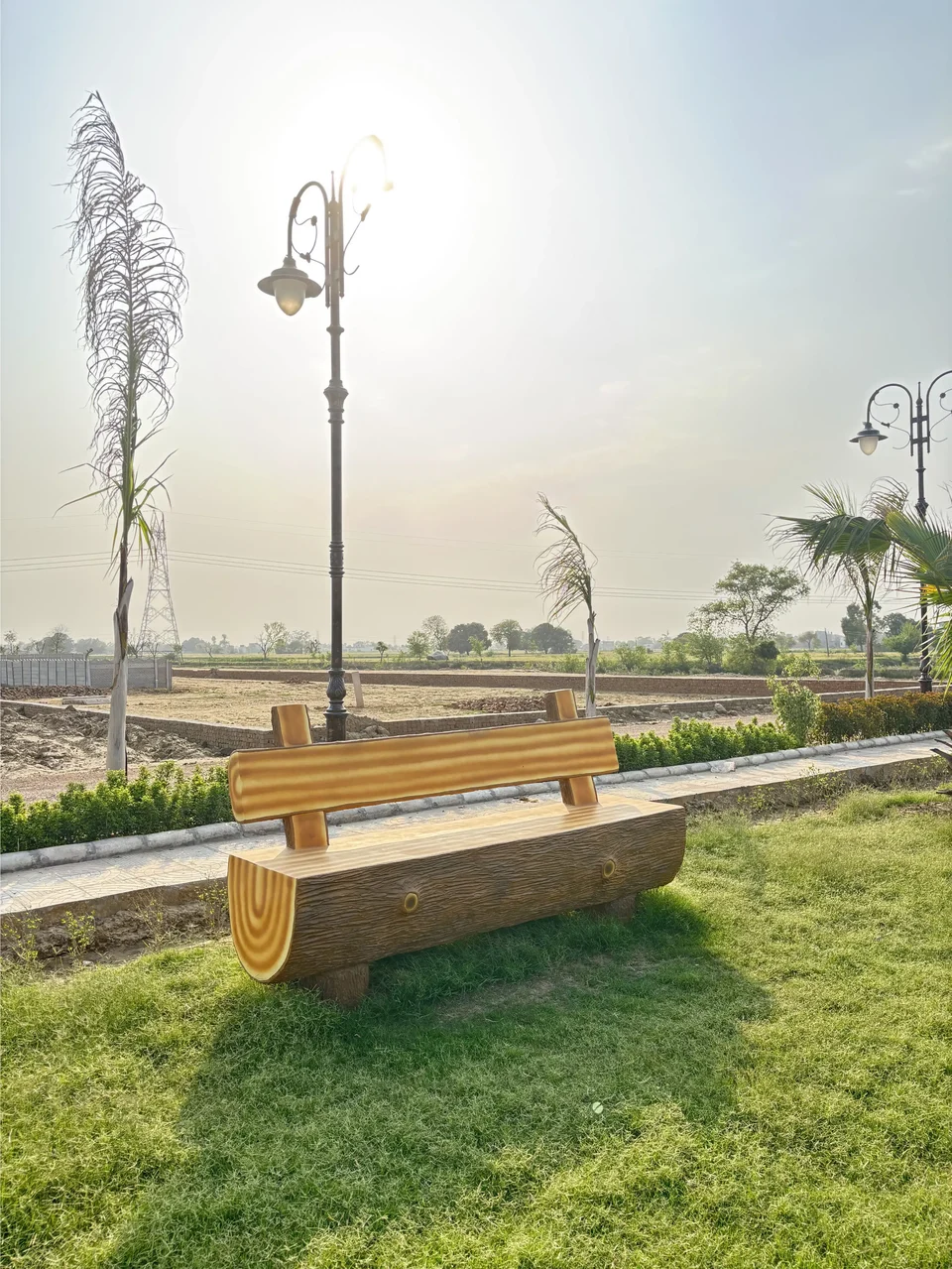 A log bench on the lawn beside a street lamp