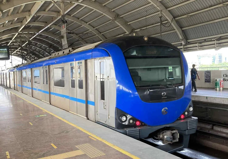 Blue and silver metro train standing at an elevated station platform beneath a curved metal roof.