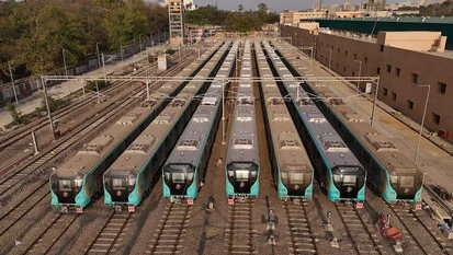 Rows of aqua-fronted metro trains parked side by side on parallel tracks in a depot yard, seen from above.