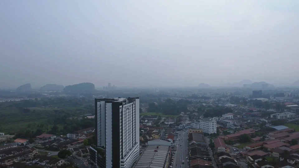 Aerial view of a city with a high-rise tower under a hazy sky
