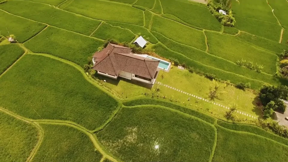 Aerial view of a villa with a pool among green fields